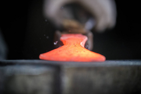 铁匠和铁锤。铁匠在锻造铁锤上使用新锤子的红热金属工件