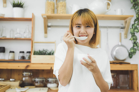 亚洲女人在家里的厨房里拿着一碗暖菜南瓜奶油汤，女人喜欢健康的营养食物。 生活方式女性放松和烹饪厨房在家里的概念。