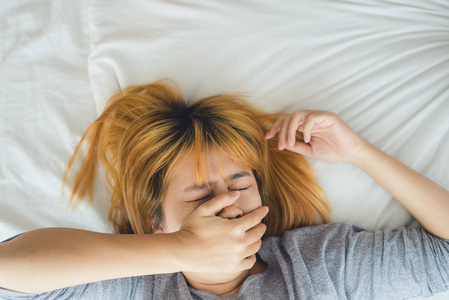 美丽的年轻亚洲女人早上睡在床上。 迷人的亚洲女孩在她舒适的卧室里睡觉。 放松卧室。 亚洲女性在家概念。