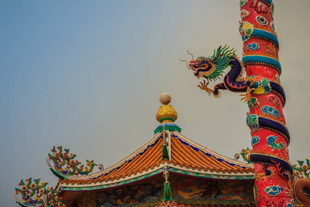 五颜六色的中国龙雕像包裹在红色的柱子上。 美丽的龙像雕刻在中国公共寺庙的庙宇杆周围。