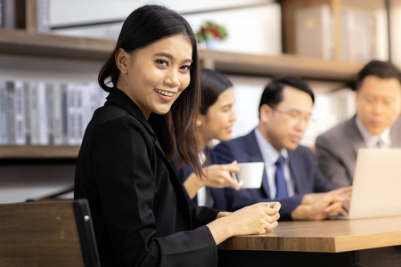自信的肖像女商人坐在咖啡馆的会议室里，背景是商业团队