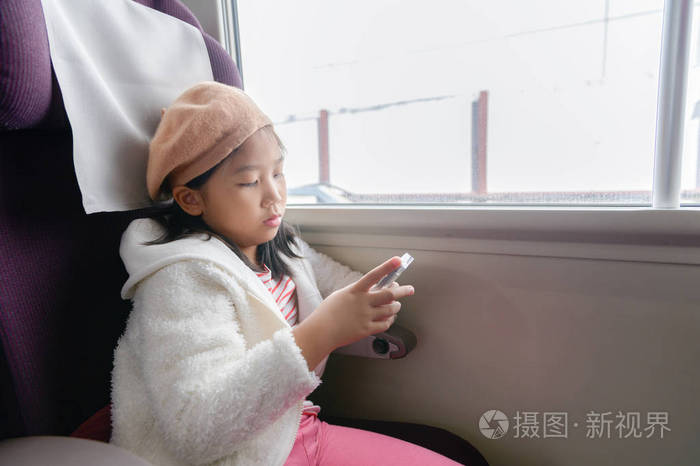 小旅行者玩手机，火车旅行或生活方式的概念