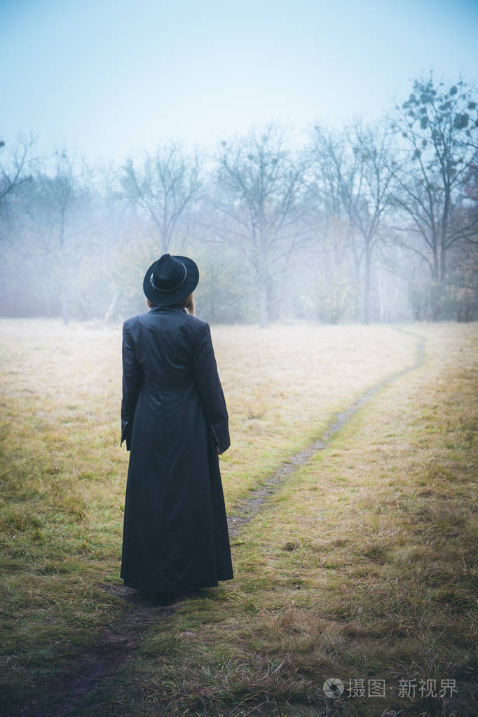 在雾中穿着黑色外套的女孩