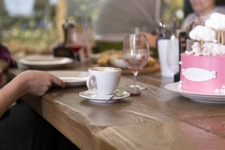 咖啡杯，蛋糕加粉白色糖霜，人们在木制餐桌上，餐桌上
