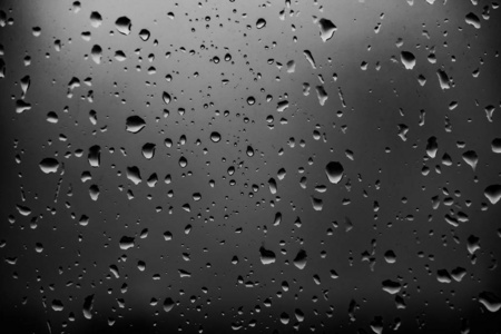 雨滴在黑暗的玻璃背景上