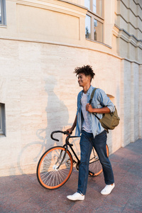 快乐的非洲年轻人在街上骑自行车走在户外的照片。