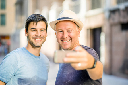 两个男性朋友在城里用智能手机自拍