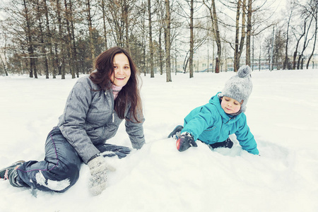 妈妈和小儿子在冬天的雪地里玩耍