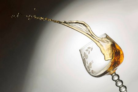 一杯透明的玻璃杯，倒着威士忌，把液体喷射出来