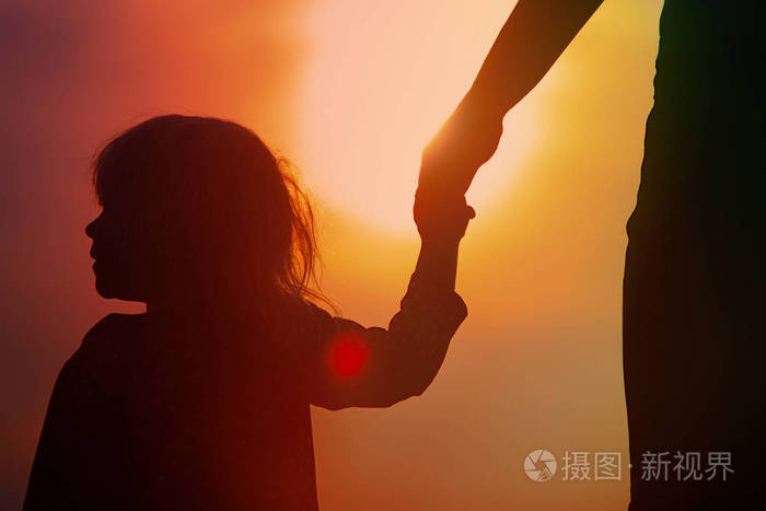 母女俩手牵着手在日落时的剪影