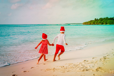 圣诞节在海滩小男孩和女孩在海上的乐趣