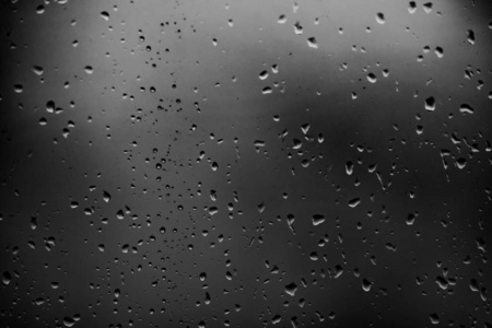 雨滴在黑暗的玻璃背景上