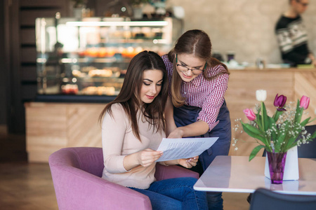 热情好客的女服务员帮助客户从菜单中选择什么东西照片