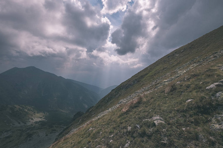 从斯洛伐克塔特拉山上的班尼科夫峰上的山景全景，岩石景观和徒步旅行者的影子在明亮的日子里，风暴云接近老式的旧电影的外观。