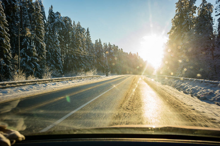 冬天的乡村道路上覆盖着冰雪，日落时有轮胎痕迹