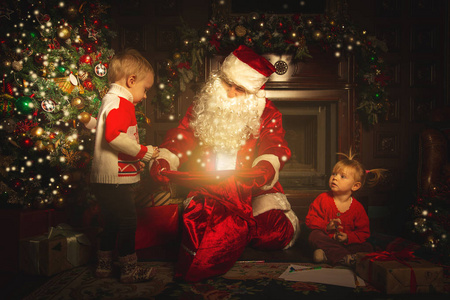 真正的圣诞老人正在圣诞树附近和孩子们玩耍。庆祝和魔法的气氛。