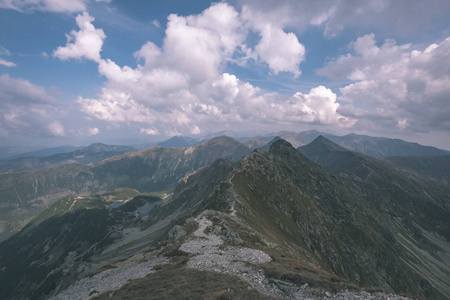 从斯洛伐克塔特拉山上的巴尼科夫峰顶的山景图，岩石景观和徒步旅行者的影子在明亮的日子里，风暴云逼近老式的旧电影外观。