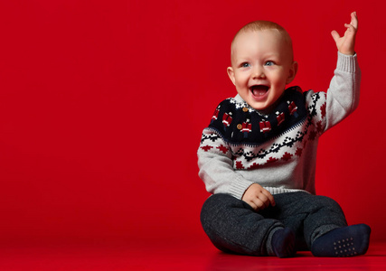 在寒冷的冬日, 有趣的小宝宝在演播室穿着温暖针织的圣诞毛衣