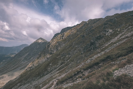 从斯洛伐克塔特拉山上的班尼科夫峰上的山景全景，岩石景观和徒步旅行者的影子在明亮的日子里，风暴云接近老式的旧电影的外观。