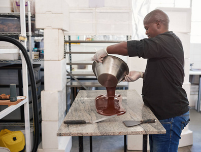 一家糖果厂的工人把融化的巧克力倒入一个碗里，混合并冷却