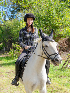 戴着黑色头盔的年轻女子骑着白马