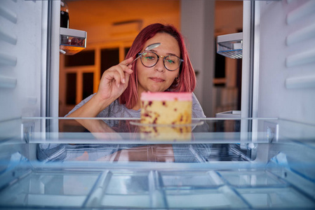 女人一边吃着门，一边站在冰箱前。 从冰箱里拍的照片。