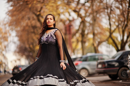 漂亮的印度女孩穿着黑色的萨雷裙在秋街户外摆姿势。