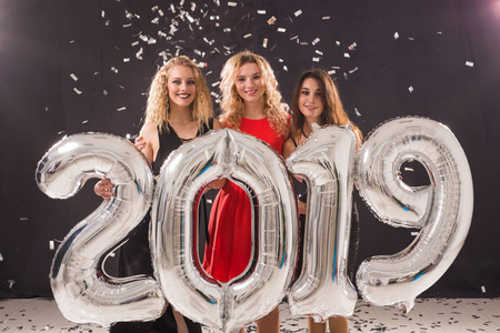 2019年新的一年即将到来。一群拿着银色数字的开朗年轻女性在聚会上