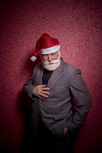 一位年长的富人打扮成圣诞老人，站在红色的背景上