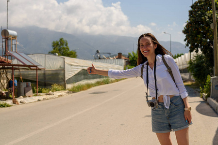 路边的徒步女孩抓车，搭便车，冒险，独立旅行。