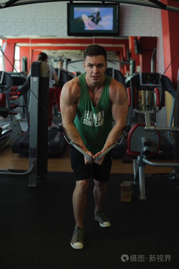 照片 年轻性感的男性健美运动员在健身房训练,使用运动设备和健身设备