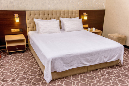 漂亮卧室里的棉床上用品。 白色床上用品，有一个圆圈的图案。 优雅的卧室，柔软的米色床。 枕套和羽绒被盖白色。 酒店卧室
