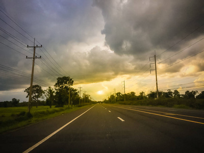 背景是暴风雨天空的沥青道路景观。 高速公路和暴风雨的戏剧性天空背景。