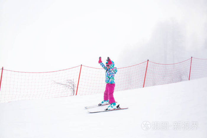 滑雪场斜坡上高山滑雪滑冰的小女孩