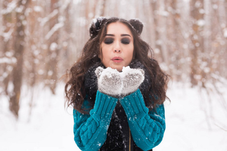 圣诞节假期和季节概念，年轻快乐的黑发女人吹雪在冬季的自然。