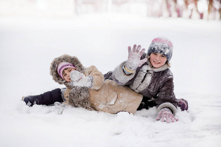 有趣的孩子们在雪地冬季公园玩耍和欢笑，快乐的姐妹