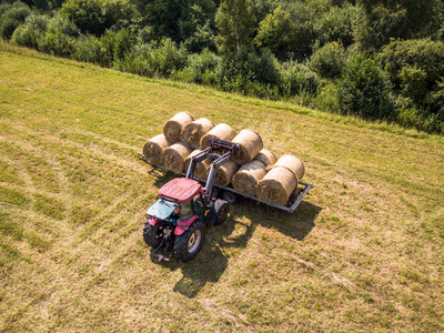 农民用红拖拉机在麦田收获干草的空中钻孔照片阳光明媚的夏日