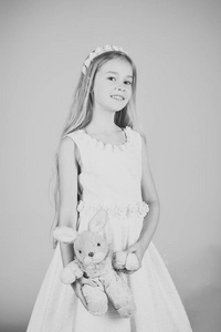 惊人的美丽年轻女孩在白色圣餐礼服的模特站在工作室与兔玩具