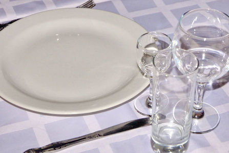 玻璃杯，酒杯，酒杯，盘子站在白色桌布上，反射光线眩光..