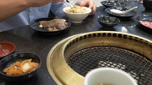 韩国烧烤烤架。人们在餐馆里做饭和吃韩国烤架上烹制的食物。特写