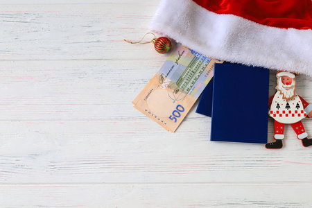 乌克兰Hryvna500格里夫尼亚，红色圣诞老人帽和蓝色护照上的旧轻型木制背景。 圣诞节新年和旅游概念。 乌克兰。 格里夫纳