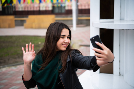 微笑的少女挥手致意, 看着手机摄像头, 快乐的年轻女士在家里做视频