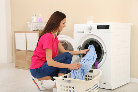 在家里用洗衣机洗衣服的年轻女子照片