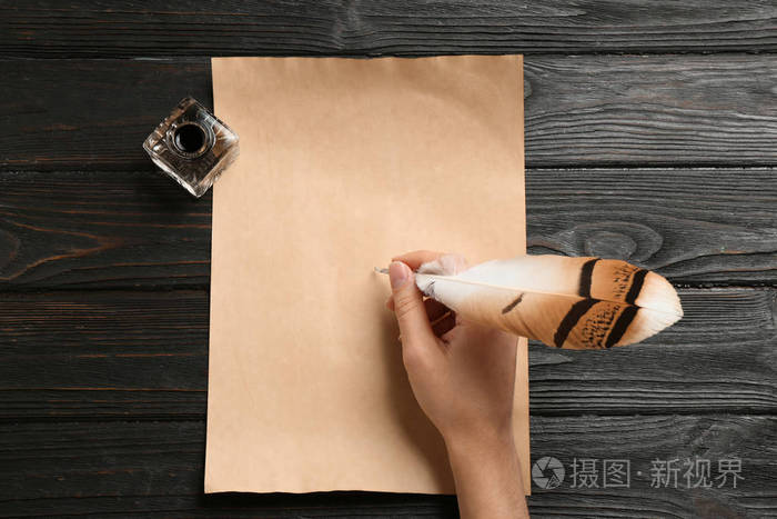女人用羽毛笔在木桌上的羊皮纸上用墨水写字文本空间