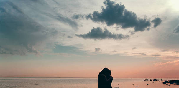 黄昏时分，一对夫妇在海滩上看着水面上的日落