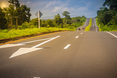 有阳光和绿色交通岛的斜坡公路. 四车道高速公路与绿色交通岛.