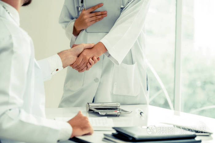 医院的医生向另一位医生握手,展示了专业医护人员的成功和团队合作.