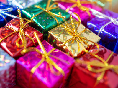 关闭小彩色礼品盒。 顶部的许多礼物包裹着五颜六色的闪亮的纸。