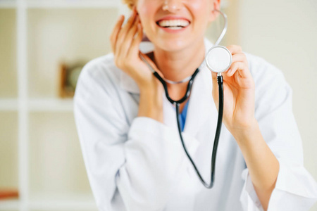 年轻的女医生把听诊器指向空白。 选择性地专注于医生的手。 医疗保健概念。