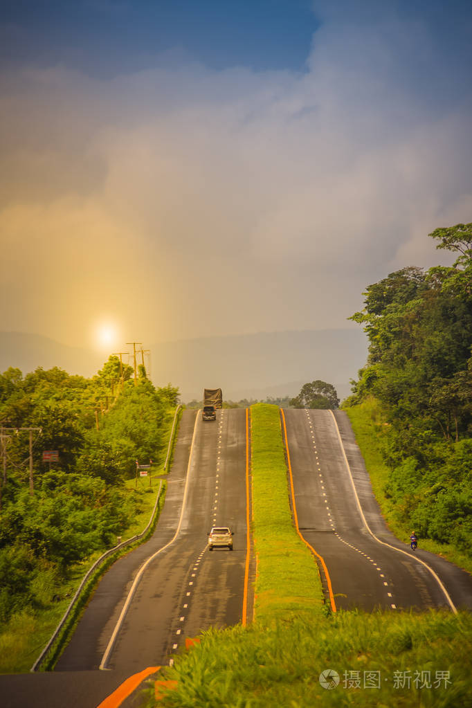 有阳光和绿色交通岛的斜坡公路. 四车道高速公路与绿色交通岛.